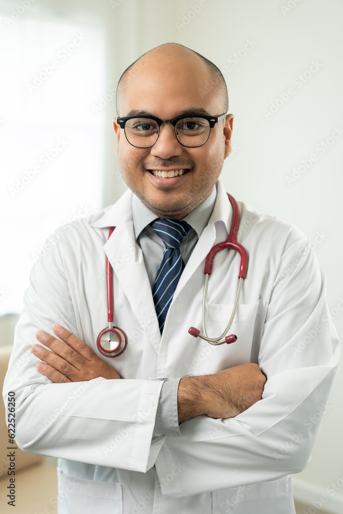 Vertical of Asian doctor standing posing work from home. Positive male physician with stethoscope looking at camera in hospital background. Healthcare and medical concept. Vertical of Asian doctor standing posing work from home. Positive male physician with stethoscope looking at camera in hospital background. Healthcare and medical concept.