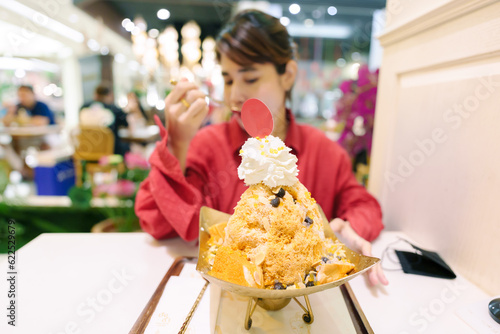 Happy woman eating shaved iced with Thai tea, bread and topping. Famous Dessert in Bangkok, Thailand