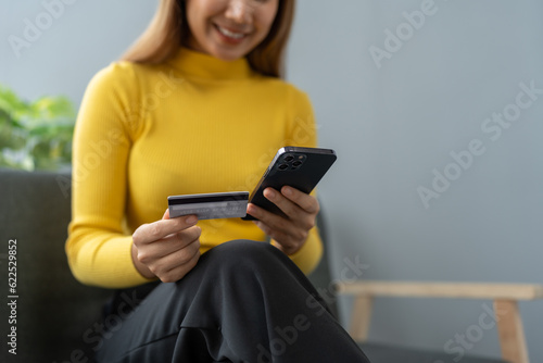 Asian businesswoman shopping online on mobile with credit card for convenient spending at home on vacation, online banking banking, e commerce virtual shopping, secure mobile banking concept.