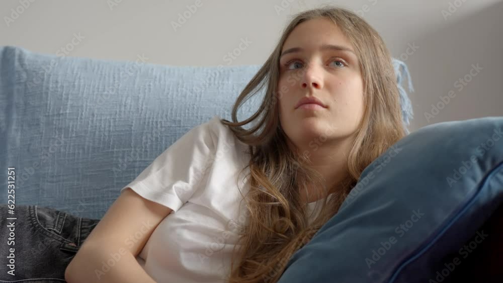 Close-up of woman using tv remote and resting head on the pillow, in Slow Motion. Girl relaxing on the sofa, watching television. Close-up of woman using tv remote and resting head on the pillow, in Slow Motion. Girl relaxing on the sofa, watching television.