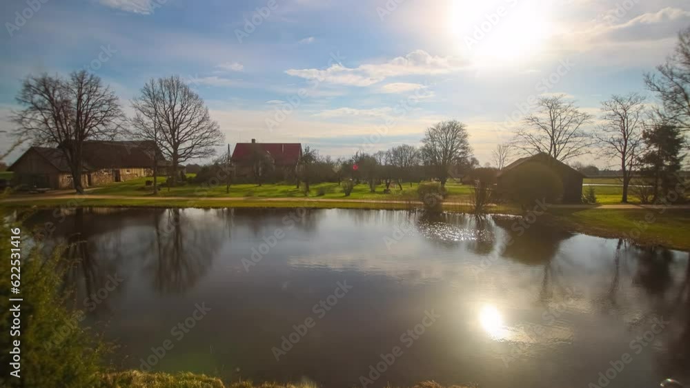 Timelapse of a sunrise at a farm, sporadic clouds pass, as the sun rises it glistens off of a lake, the land and trees. Timelapse of a sunrise at a farm, sporadic clouds pass, as the sun rises it glistens off of a lake, the land and trees.