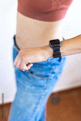 Close up girl in denim shorts looking at her watch.