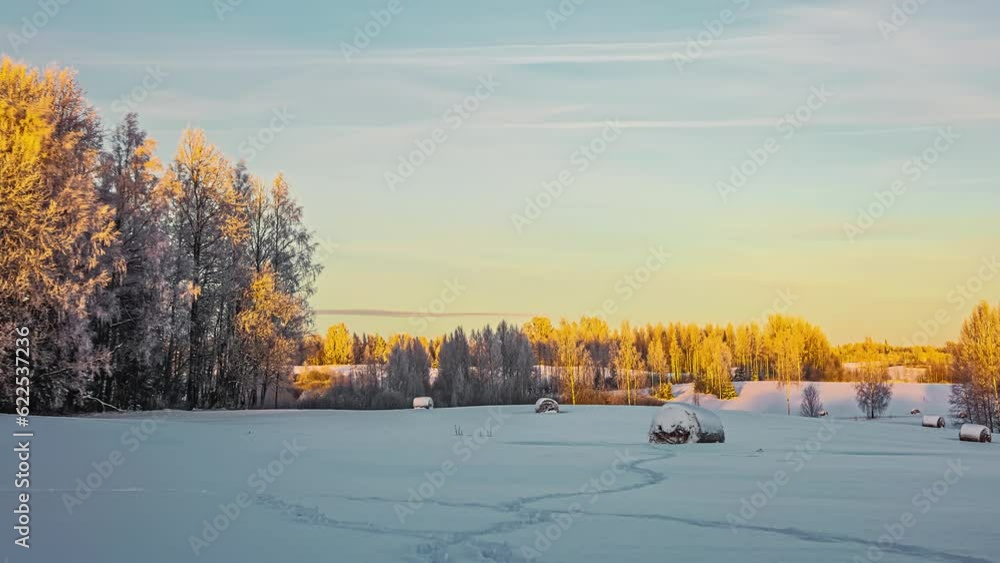 Timelapse of farmland, trees and hay bales covered with snow, as the sun reflects off the landscape and the trees gently blow in the breeze. Timelapse of farmland, trees and hay bales covered with snow, as the sun reflects off the landscape and the trees gently blow in the breeze.