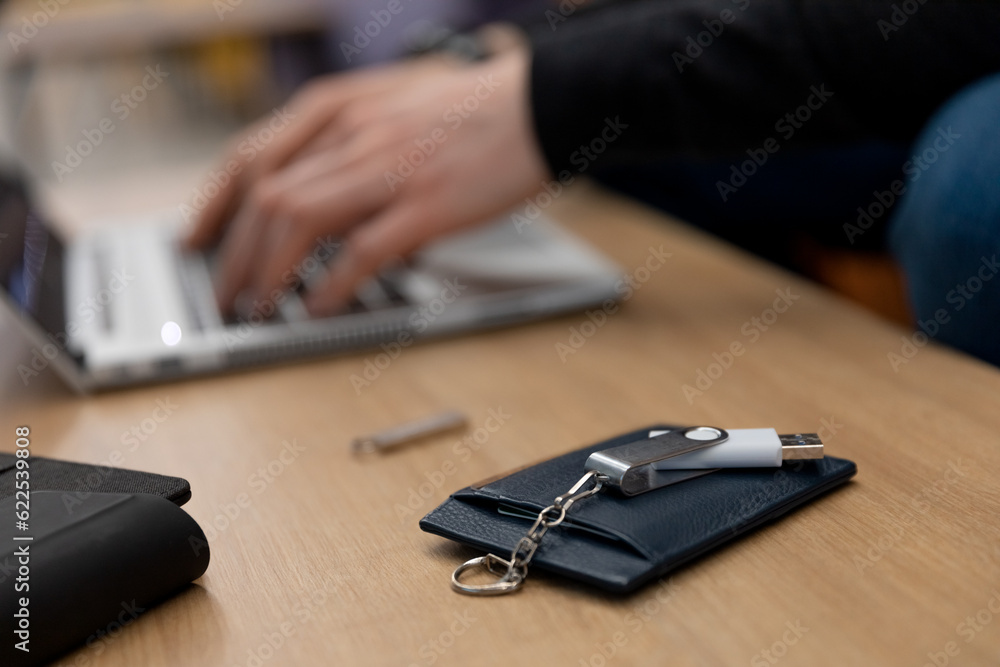 Fototapeta premium Card holder lies on wooden table next to programmer typeing on the lap top