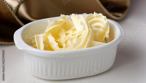 Rolled creamy butter shavings in an individual little white china ramikin for a formal catered dinner or event