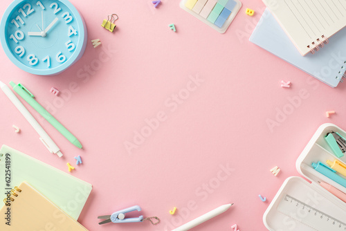 Brighten up your study routine! Top-down view of back-to-school essentials—copybooks, pens, binder clip, clock, alphabet letters—arranged on a pastel pink background. Plenty of space for text or ads