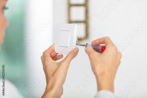 cropped view of woman using screwdriver to align light switch