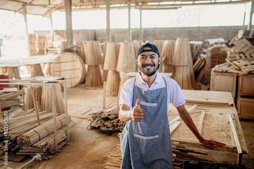 entrepreneurial man gives thumbs up while standing in a woodworking workshop