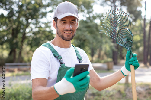 Canvas Print smiling gardener looking at his phone