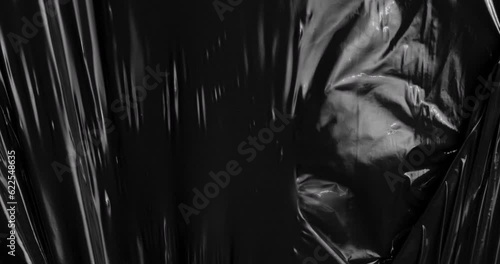 Surrender to the spellbinding charm of stretched plastic film as it merges with the depths of black, unveiling a tactile dreamscape that echoes the intricate beauty of rumpled cellophane wrap.