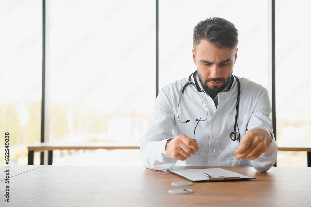 Young doctor sitting in his office behind a desk Young doctor sitting in his office behind a desk
