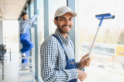 Male janitor cleaning window in office photo