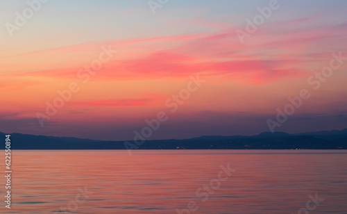 Sunset sky with red cloud above sea and distant hill. Travel, nature background, Croatia, island Krk