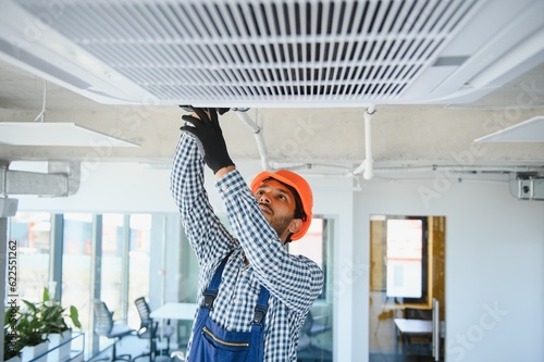 Fototapeta Professional technician maintaining modern air conditioner indoors