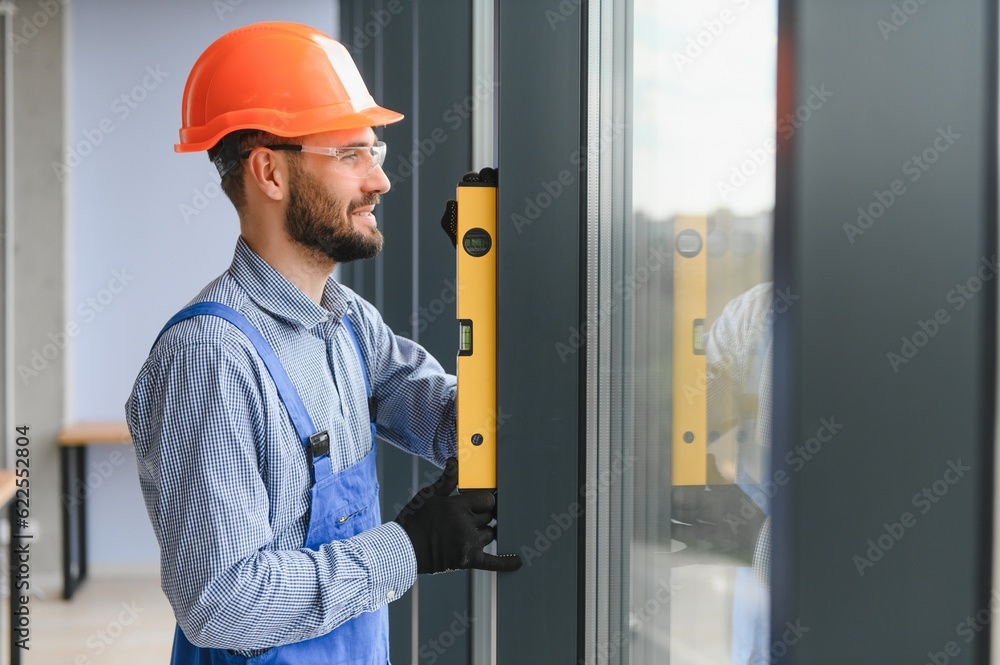 Worker installing plastic window indoors. Worker installing plastic window indoors.