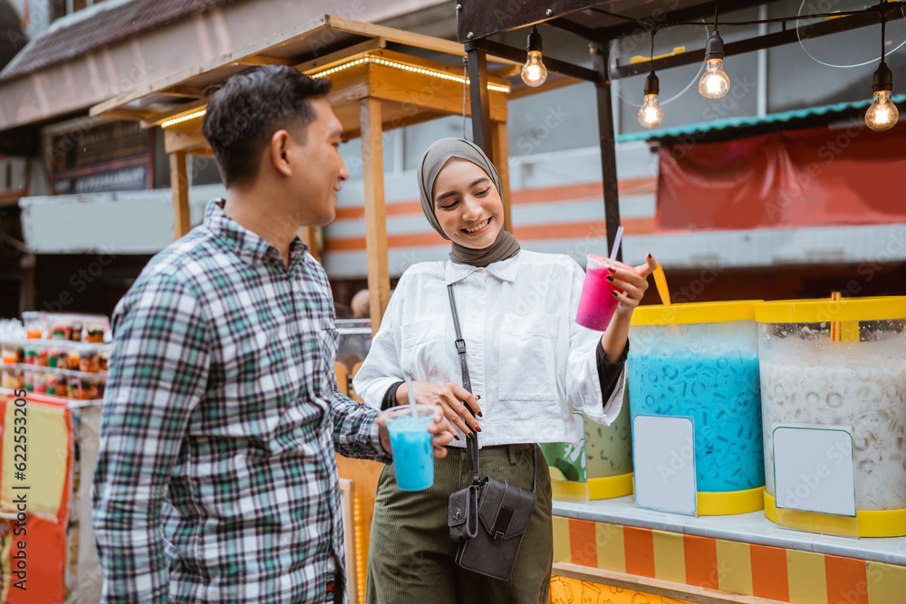 portrait of happy young muslim couple buy drink from a street vendor
