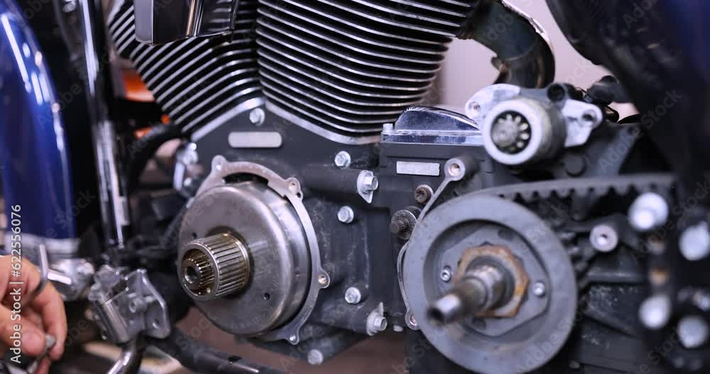 Mechanic using wrench and socket on motorcycle cylinder head. Maintenance and repair of a motorcycle in a garage concept Mechanic using wrench and socket on motorcycle cylinder head. Maintenance and repair of a motorcycle in a garage concept