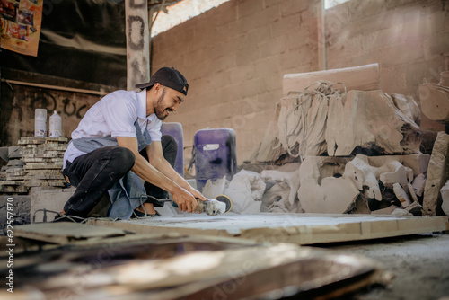 male workers in hats use tools to polish stone crafts in the workshop
