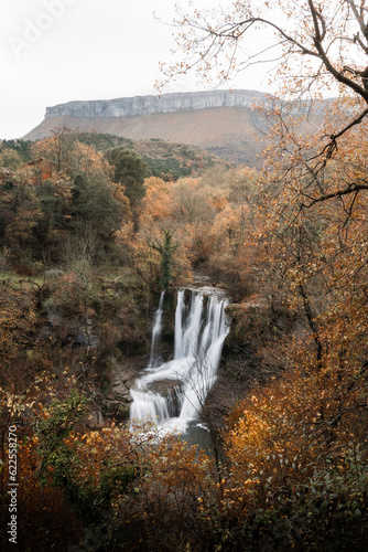Autumn landscape of the Peñaladros waterfall and the Ayala valley with the Gorobel or Sierra Salbada mountain range in the background photo