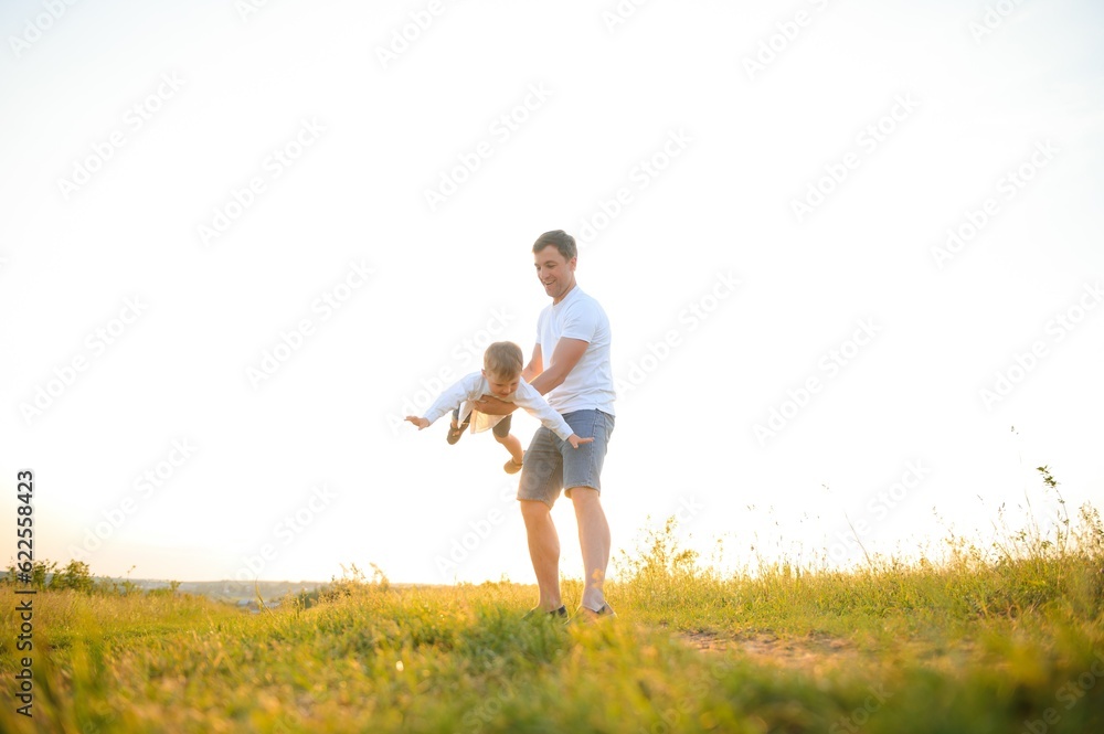 Happy father, son child running playing in the park outdoors together. Family, Father's Day, parenting, active lifestyle concept.