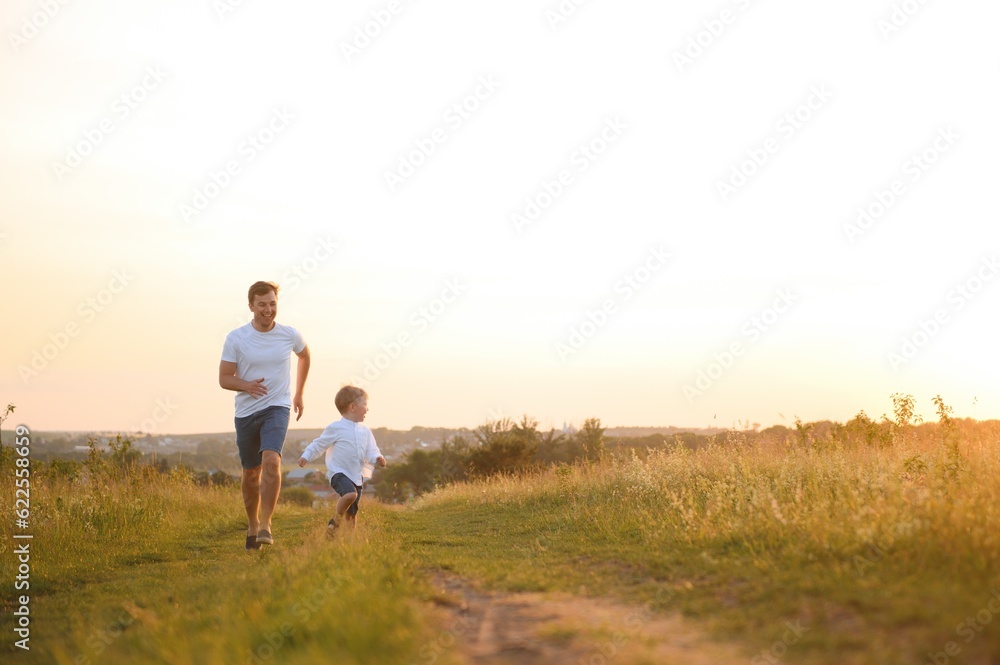 Father's day. Happy family father and toddler son playing and laughing on nature at sunset Father's day. Happy family father and toddler son playing and laughing on nature at sunset