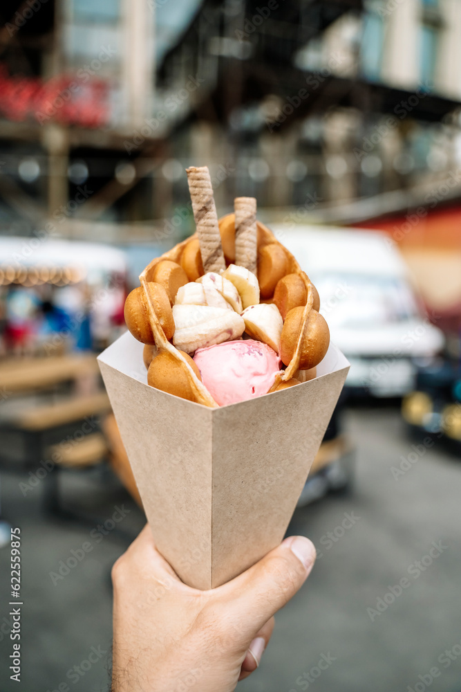 Street food dessert Belgian waffles in hand on a colored wall background. Sweets, street food