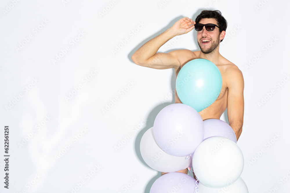 Funny Laughing Caucasian Handsome Brunet Man With Bunch of Colorful Air Balloons in Hand While Posing in Underware Against White Funny Laughing Caucasian Handsome Brunet Man With Bunch of Colorful Air Balloons in Hand While Posing in Underware Against White