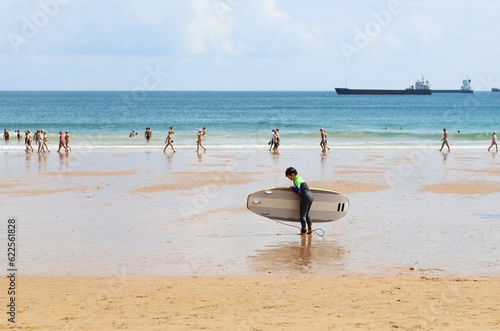 Fototapeta Naklejka Na Ścianę i Meble -  A child with a surfboard. Surfer school in summer, on a beach
