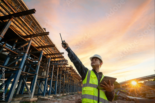 Valokuva Mature engineer architect in safety and helmet costume working on a tablet on a tollway construction site