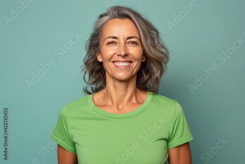 smiling middle aged woman in green t-shirt on blue background © igolaizola