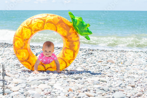 little girl with a giant rubber swim ring at the water's edge on the beach