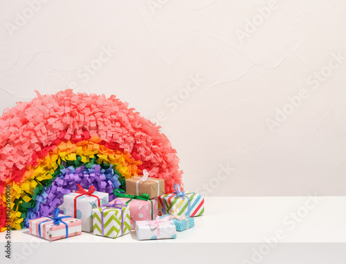 Rainbow pinata and colorful gifts wrapped in beautiful paper with gift bows. Copy space for text.