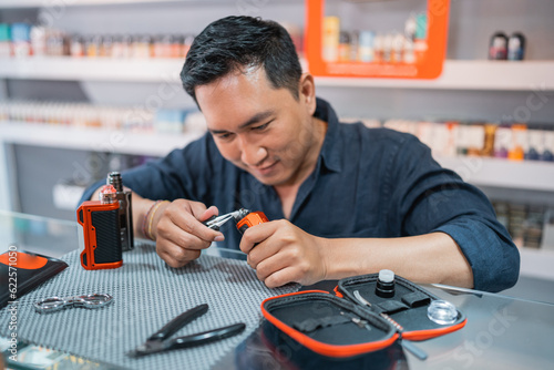 male shopkeeper changing the vape cotton coil seriousely at the vape store photo