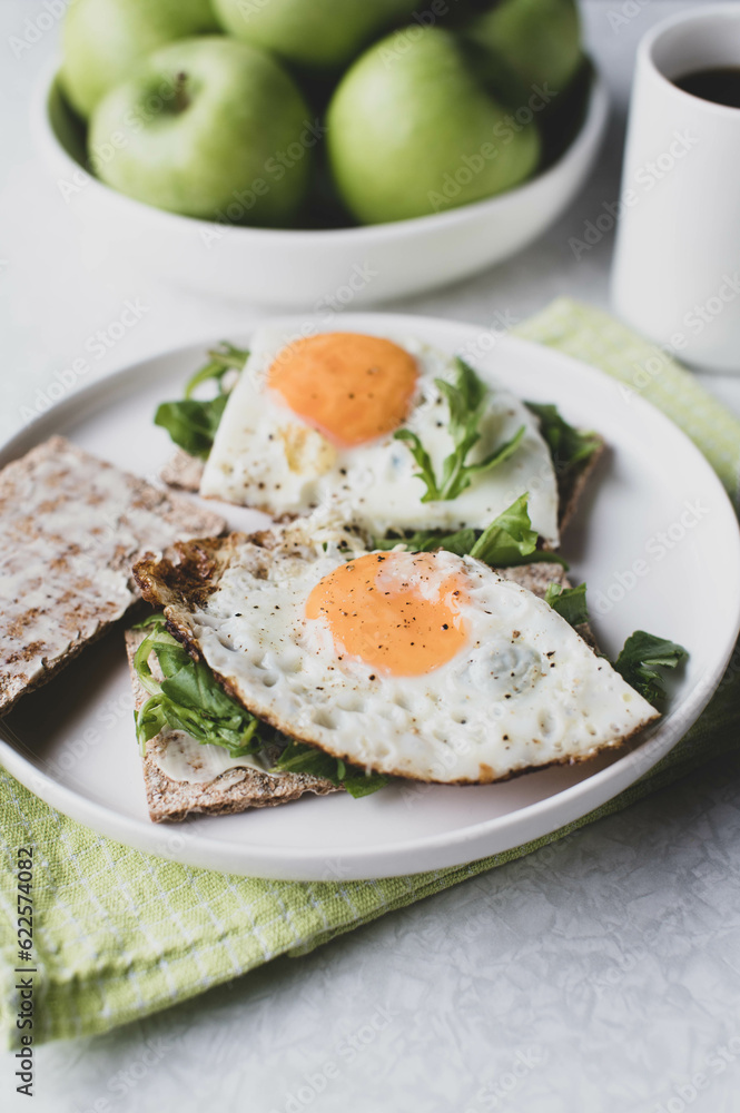Vegetarian breakfast sandwich with organic crispbread, arugula and fried eggs. 