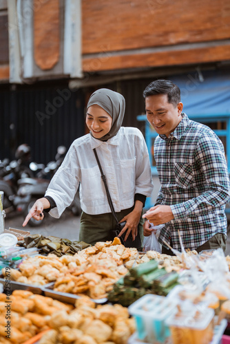 beautiful muslim couple are shopping in a food stall or street vendor during ramadan