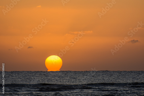 sunrise with a glowing distorted orange sun at the horizon from the red sea in marsa alam egypt