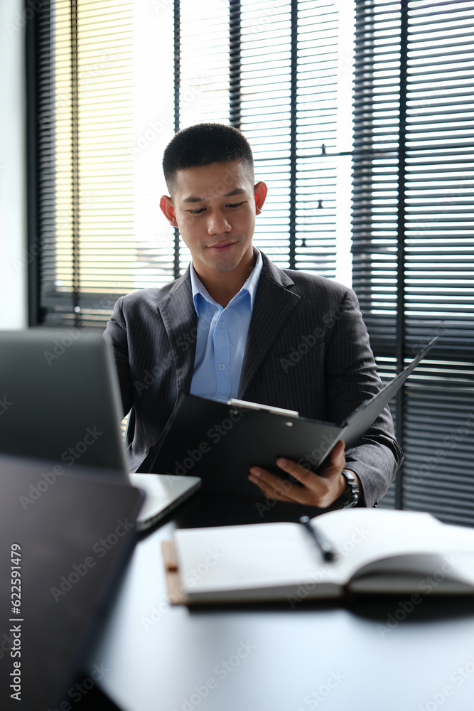Portrait of young businessman using laptop and analyzing work results at workstation Portrait of young businessman using laptop and analyzing work results at workstation