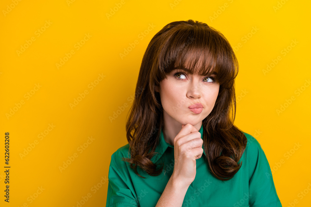 Photo of suspicious unsure lady wear green shirt arm chin looking empty space isolated yellow color background Photo of suspicious unsure lady wear green shirt arm chin looking empty space isolated yellow color background