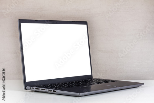 white mock-up on a laptop screen on a white table against a gray wall close-up