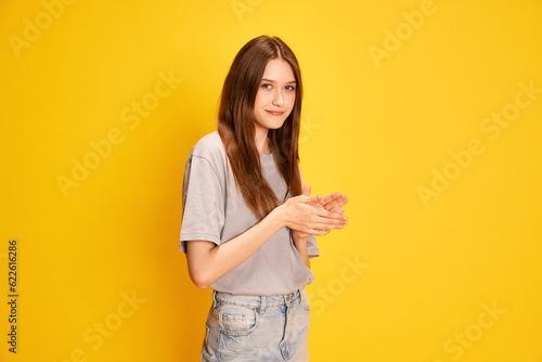 Portrait of young beautiful girl, student in casual clothes posing against yellow studio background. Smiling. Concept of human emotions, fashion, youth, lifestyle, female beauty, ad