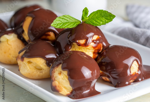 Fotografía Delicious profiteroles with chocolate and white plate