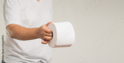 Hand holding a tissue and a painful stomachache while standing on a gray background.