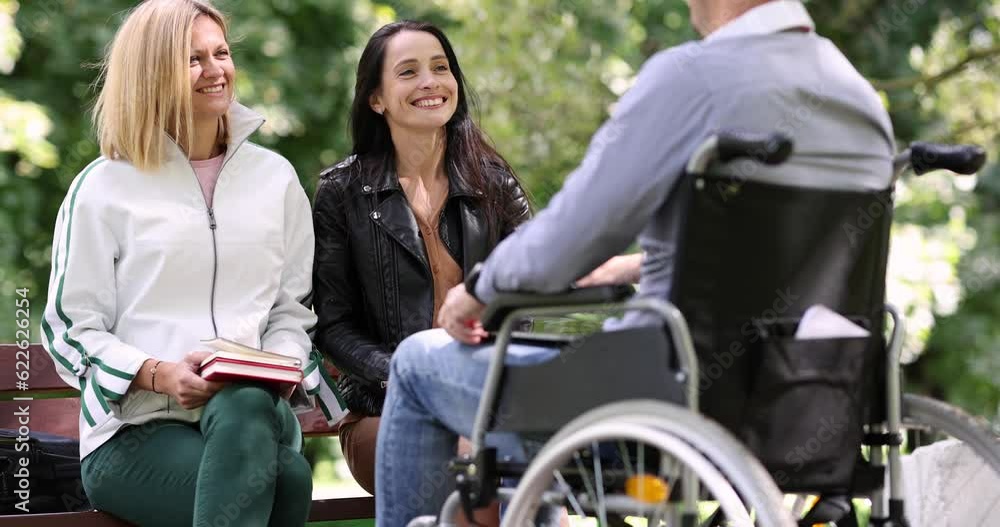 Disabled man in wheelchair communicating with friends in park 4k movie. Full life of people with disabilities social adaptation concept Disabled man in wheelchair communicating with friends in park 4k movie. Full life of people with disabilities social adaptation concept