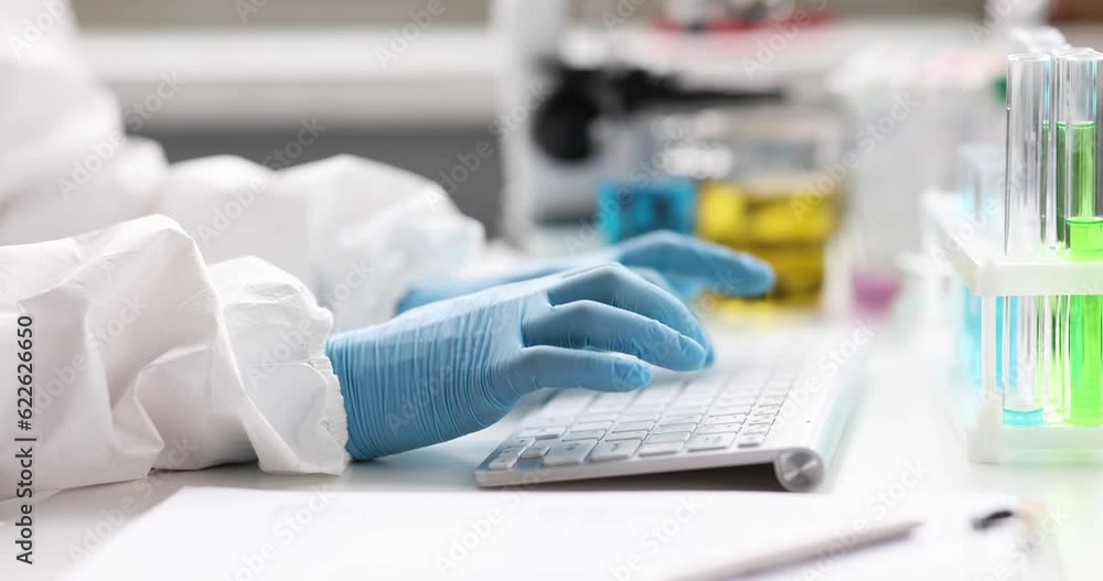 Scientist chemist in protective suit and gloves typing on keyboard near test tubes in laboratory 4k movie. Development of vaccine against covid19 concept Scientist chemist in protective suit and gloves typing on keyboard near test tubes in laboratory 4k movie. Development of vaccine against covid19 concept