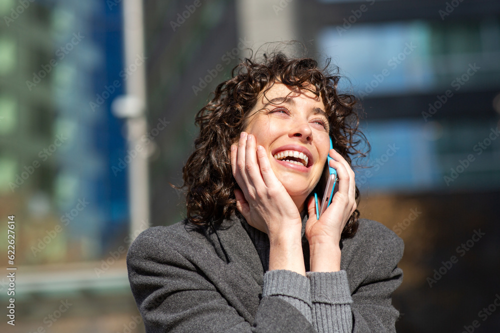 Young woman talking on mobile phone and laughing outside in the city Young woman talking on mobile phone and laughing outside in the city