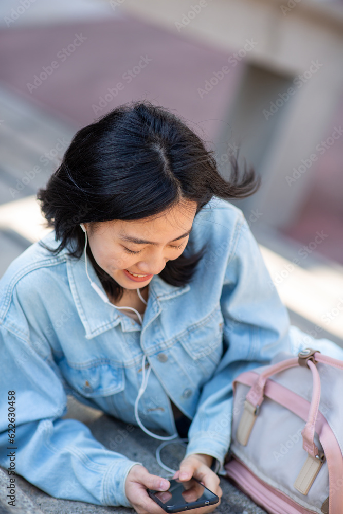 Portrait young woman sitting with mobile phone and listening with earphones Portrait young woman sitting with mobile phone and listening with earphones