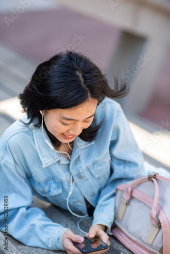 Portrait young woman sitting with mobile phone and listening with earphones