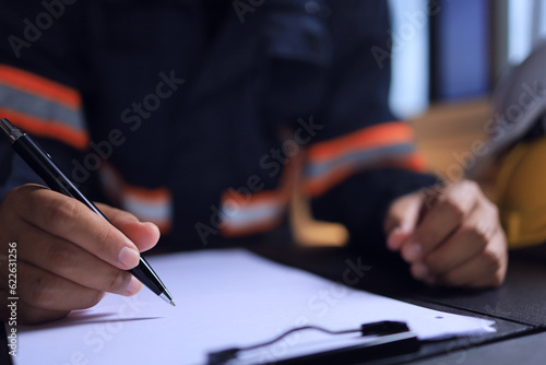 An engineer is using a pen to write notes on white paper about the progress of daily work for a report to be sent to the project leader. The strength of the planning structure and the budget. photo