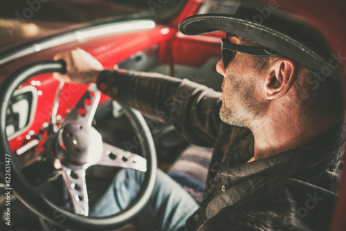 Caucasian American Cowboy Behind Vintage Classic Pickup Wheel