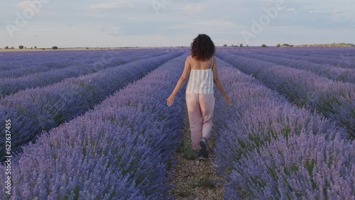 Wallpaper Mural Woman walks by blooming lavender fields with blue lavender flowers in summer day. Farm for the production of lavender oil. Torontodigital.ca